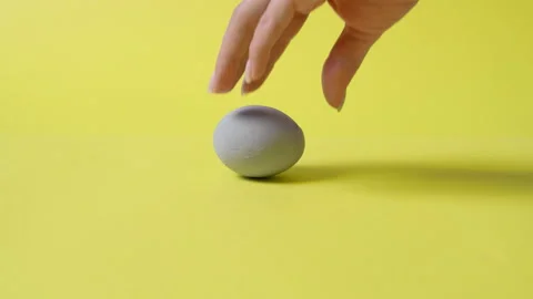 Gray colored egg on a yellow background. Easter Stock Footage 146585949
