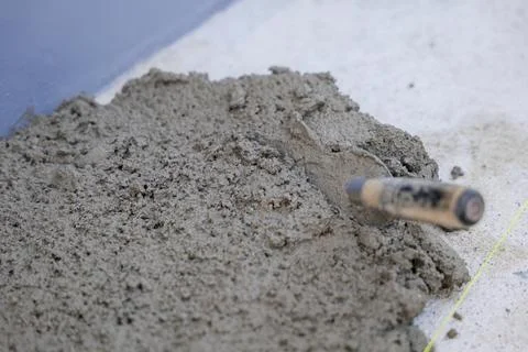 Gray concrete surface with a trowel, pull tabs, and wedges, showcasing the .. Fotos Stock