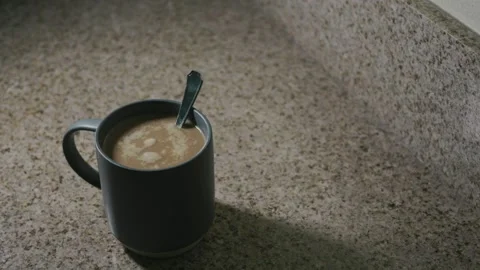Gray cup of coffee on a granite countertop after being stirred Stock Footage 309469797