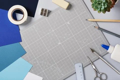 Gray cutting mat surrounded by colored paper and craft tools on a desk. Cre.. Stock Photos