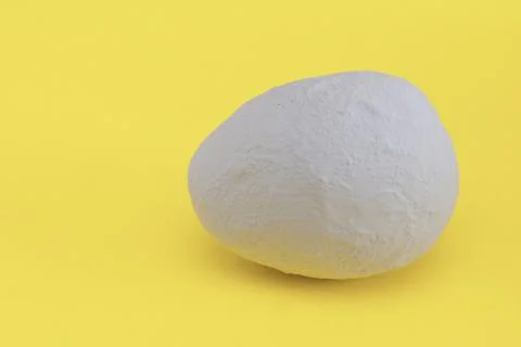 A gray decorative egg on a light yellow background. Stock Photos