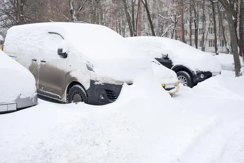 Gray delivery van and two sedans stand buried in snow piles Stock Photos