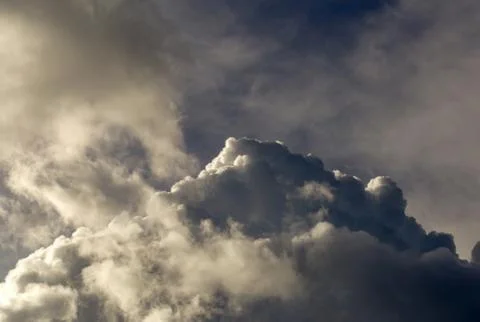 A gray dense cumulus clouds begins to gather in the blue suny sky over the An Stock Photos