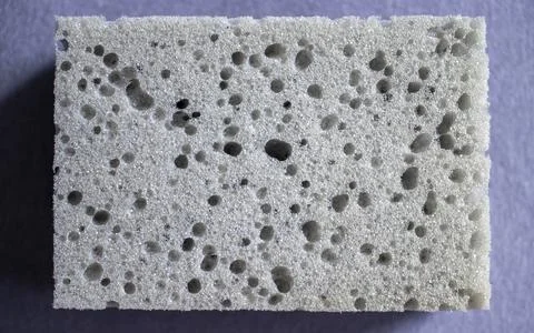Gray dishwashing sponge on a gray background. Stock Photos