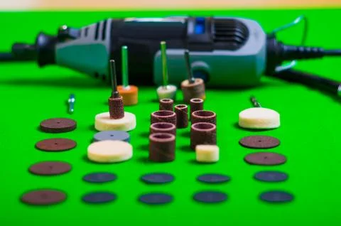 A gray drill behind of the drilling accessories on green background Stock-Fotos