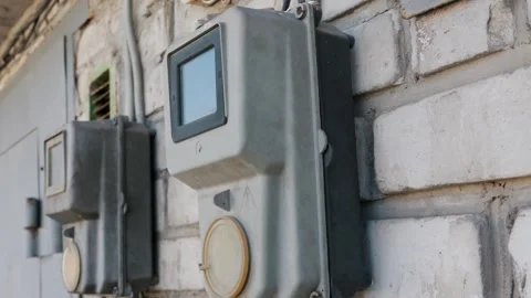 Gray electrical power meters mounted on a white exterior brick wall. Vídeos de archivo 331267107