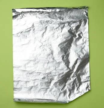 Gray foil for baking and packaging food on a green background Stock Photos
