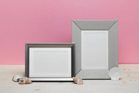 Gray frames with shells on white desk near pink wall Stockfoto's