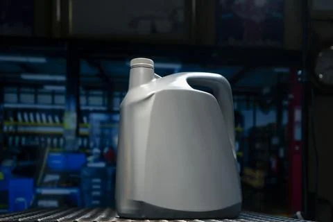A gray gallon or bottle of engine oil sits on a metal table in a profession.. Stockfoto's