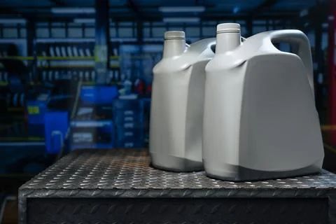 A gray gallon or bottle of engine oil sits on a metal table in a profession.. Фото