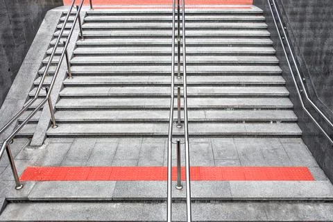 Gray granite staircase with steps and stainless steel handrail. Stock Photos