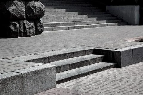 Gray granite steps in the middle of stone tile street pavement. Stock Photos