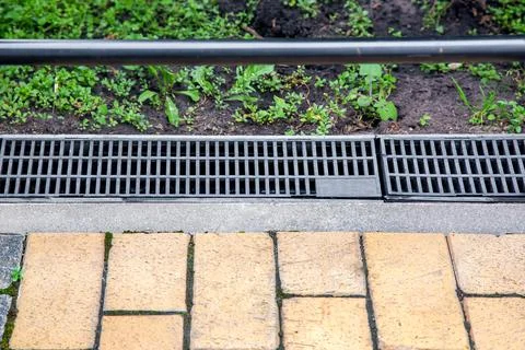 Gray grating of the drainage system for drainage of rainwater. Stock Photos