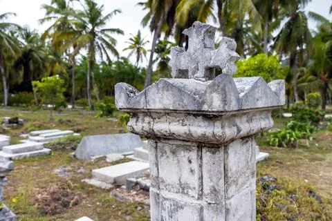 Gray gravestone with cross on top mounted at La Digue cemetery Stock Photos