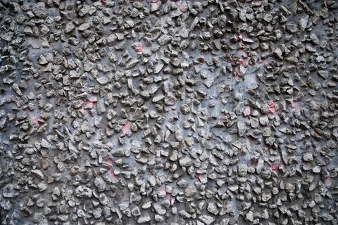 Gray grungy conctrete wall texture with gravel stones integrated in it Stock Photos