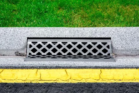 Gray gutter of a stormwater drainage system on the side of asphalt road. Stock Photos