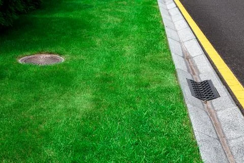Gray gutter of a stormwater system on the side of asphalt road. Stock Photos