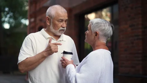 Gray-haired elderly couple happily chatting on urban street with coffee cups Stock Footage 289779851