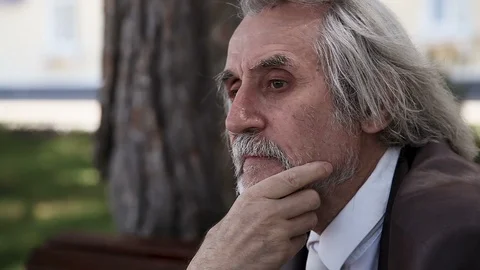 Gray-haired elderly man with a beard in a suit thinking and stroking his beard Video stock 96514074