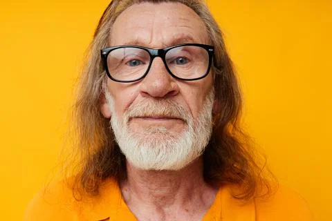 Gray-haired elderly man with a beard wearing glasses close up yellow background Stock Photos