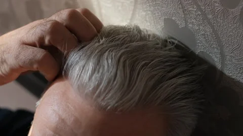 A gray-haired elderly man scratches his head while thinking about something Video stock 266936478