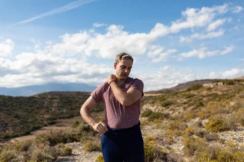 A gray-haired man adjusts his clothes and T-shirt during a walk in the Foto stock