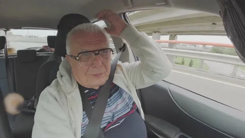 Gray-haired man drives car and puts on hood cabin view Stock Footage 148388685