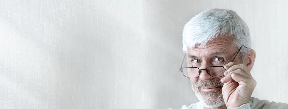 Gray-haired man in light clothes and glasses enters into a contract on paper 写真素材