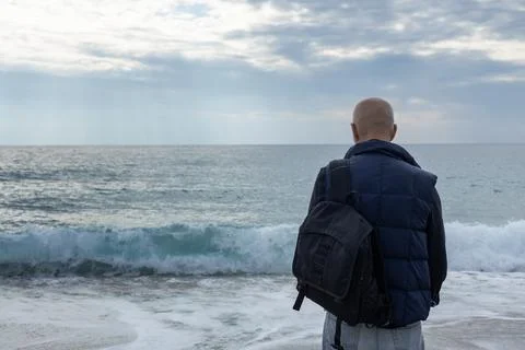 Gray-haired man overlooking the sea. tourist with a backpack Stock Photos