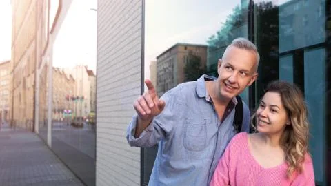 A gray-haired man is showing something in the distance to a young woman. Stock Photos