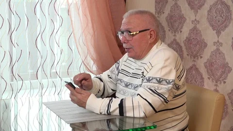 Gray haired man sits touches phone shows green screen Stock Footage 108605081