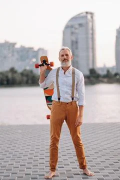Gray-haired man with skateboard. Stock Photos