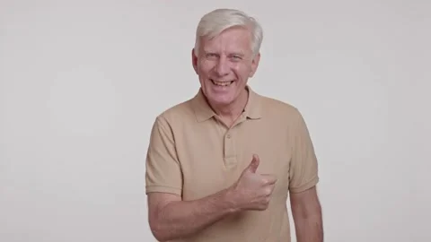 Gray haired man smiles to camera. showing thumb up sign on a white background Stock Footage 262016663