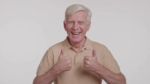 Gray haired man smiles to camera. showing thumb up sign on a white background Stock Footage 262016684