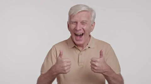 Gray haired man smiles to camera. showing thumb up sign on a white background Stock Footage 262016700