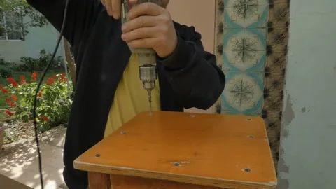 A gray-haired man tightens a screw with an electric drill Vídeos de archivo 162958547