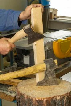 A gray-haired man in work clothes works with an axe. chops the log. carpenter's Stock Photos