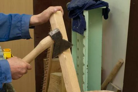 A gray-haired man in work clothes works with an axe. chops the log. carpenter's Stock Photos