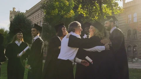 Gray-haired middle aged man congratulating male and female graduates of mixed Stock Footage 83602059
