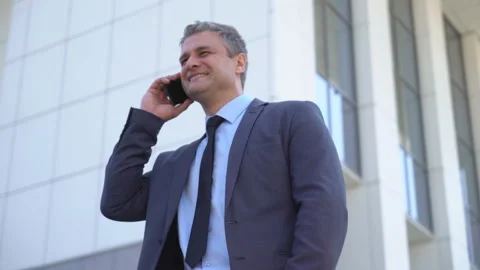 A gray-haired middle-aged man in a suit is looking at the camera against the Stock Footage 91044332