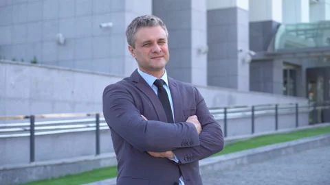 A gray-haired middle-aged man in a suit looks at the camera against the backdrop Stock Footage 91044563