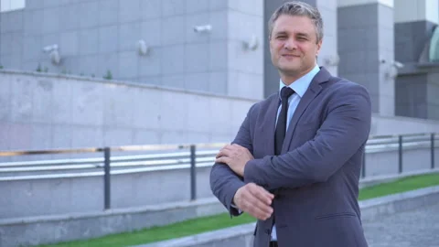 A gray-haired middle-aged man in a suit looks at the camera against the backdrop Stock Footage 91044784