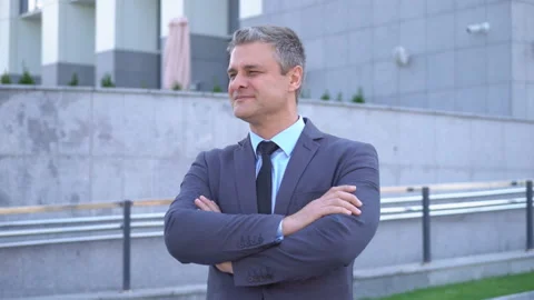A gray-haired middle-aged man in a suit looks at the camera against the backdrop Stock Footage 91045026