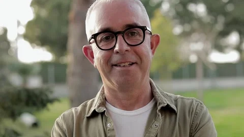 Gray-haired middle aged man in black glasses stand in front of green background Stock Footage 150945580