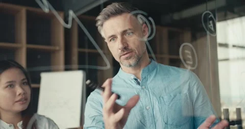 A gray-haired, middle-aged man Visualizes his plan with a glass board and a Stock Footage 243454571
