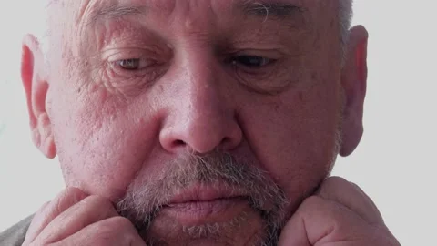A gray-haired old man sits thoughtfully with his face covered with his hands Stock-Footage 154296185