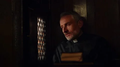 The gray-haired pastor opens the window in the confessional and listens Stock Footage 234496368
