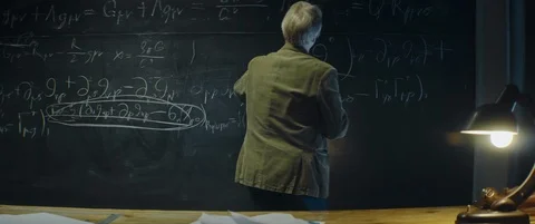Gray haired Professor erases formula or equation from blackboard late at night Stock Footage 123126601