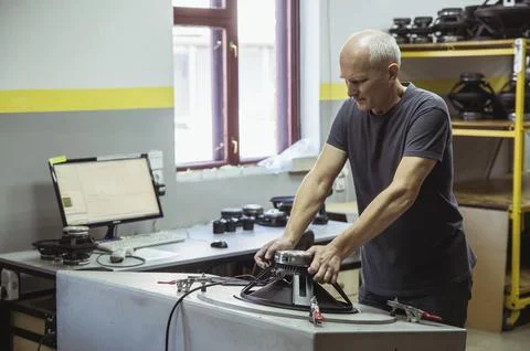 Gray-haired worker testing audio speaker at factory Stock Photos