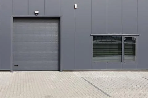 Gray industrial wall with roller shutter door and window. Stock Photos